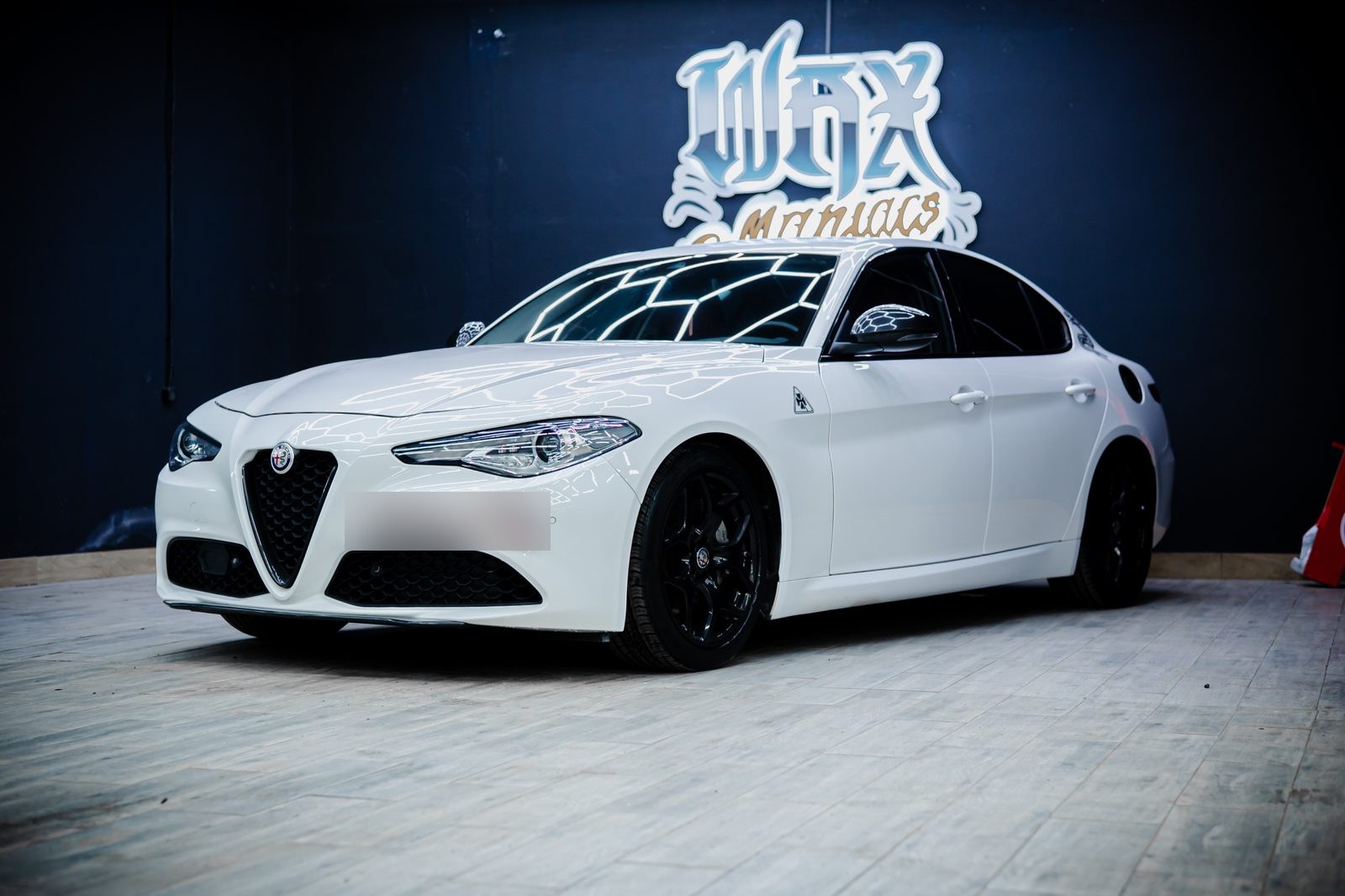 Белая Alfa Romeo Giulia в боксе студии под гексагональными лампами